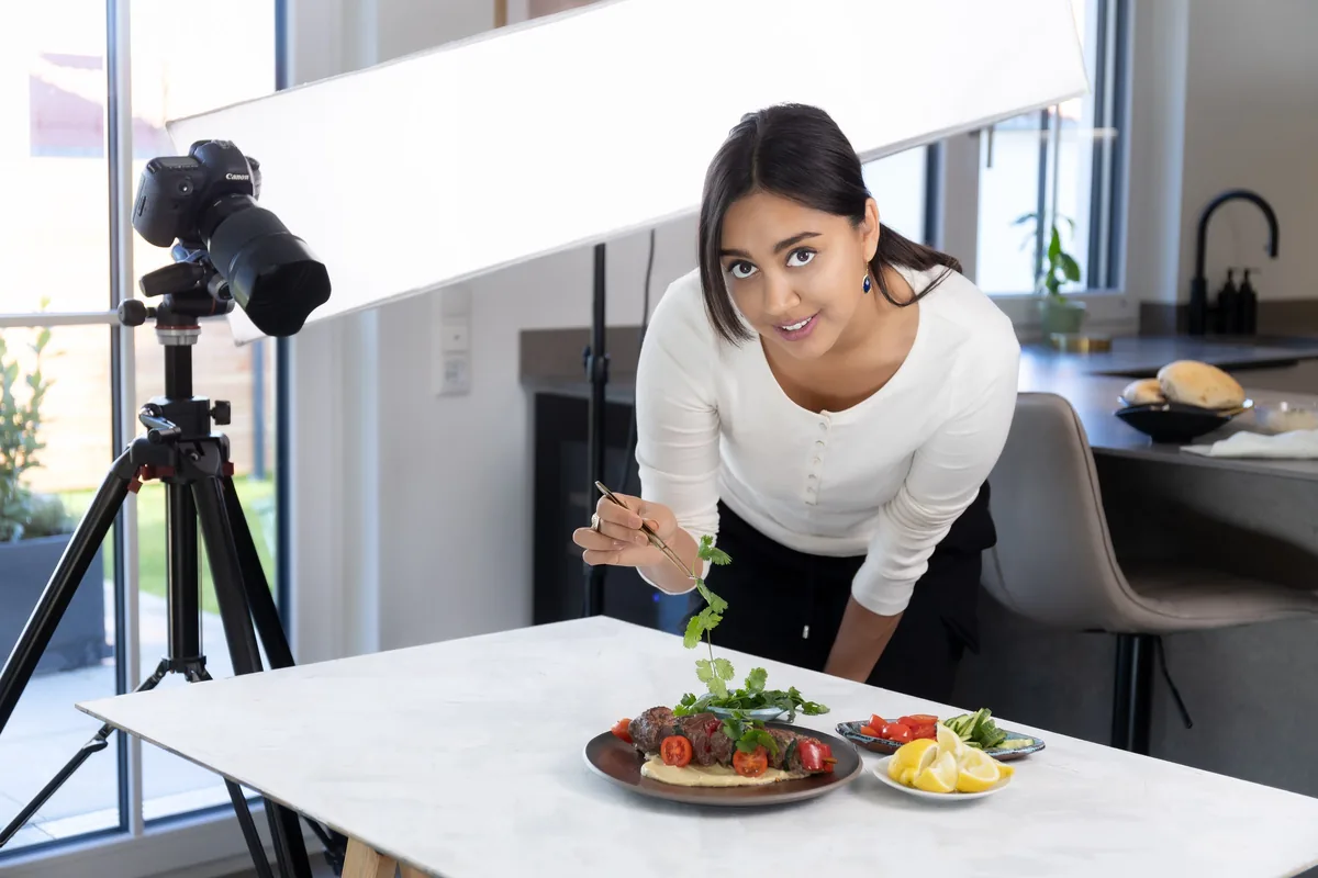 Chef Ivana Sanshia finishing a plated dish on a photography set in her kitchen